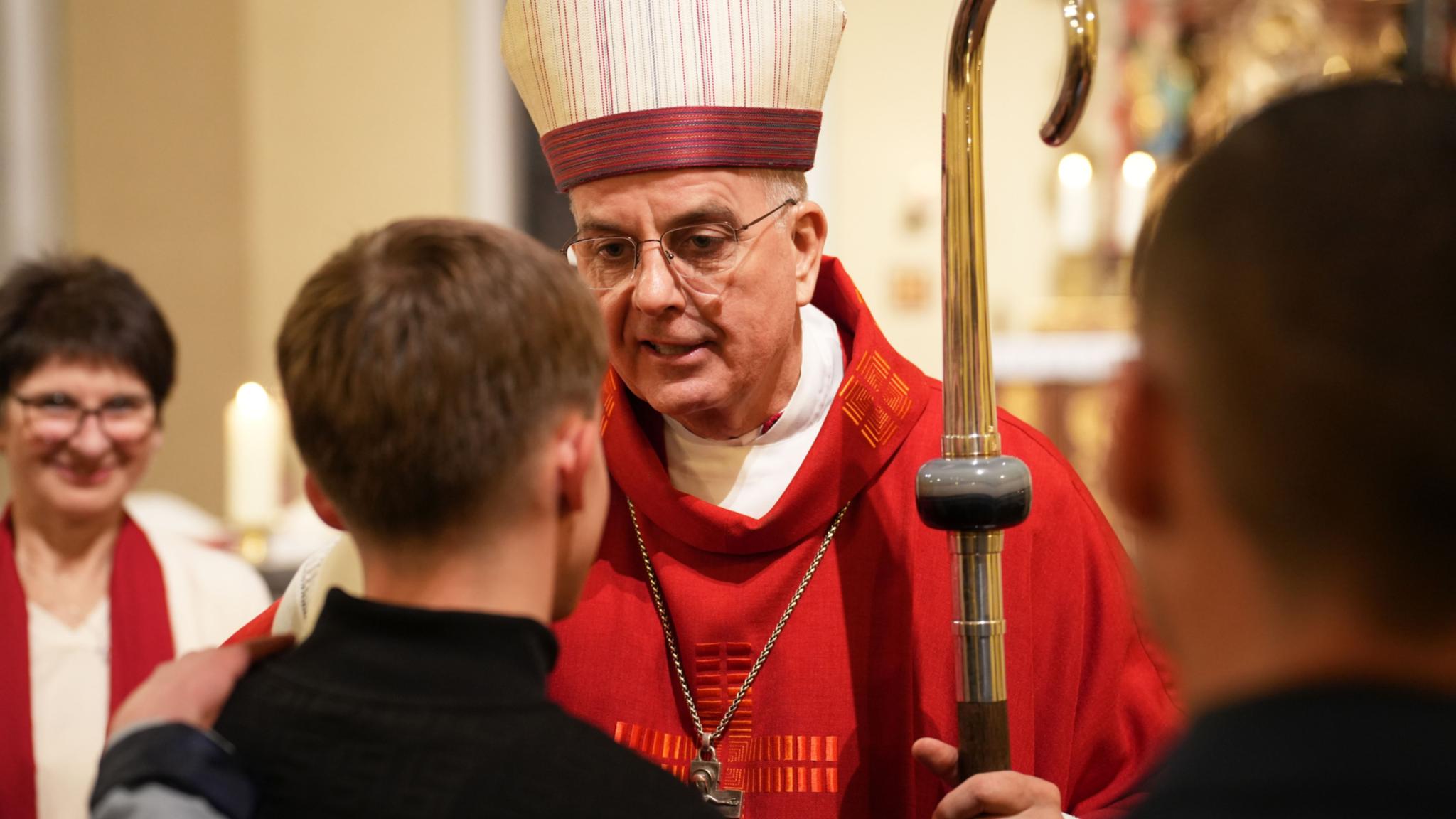 Weihbischof Peters spendet den jungen Menschen in der Kirche St. Maximin in Bettingen das Firmsakrament.