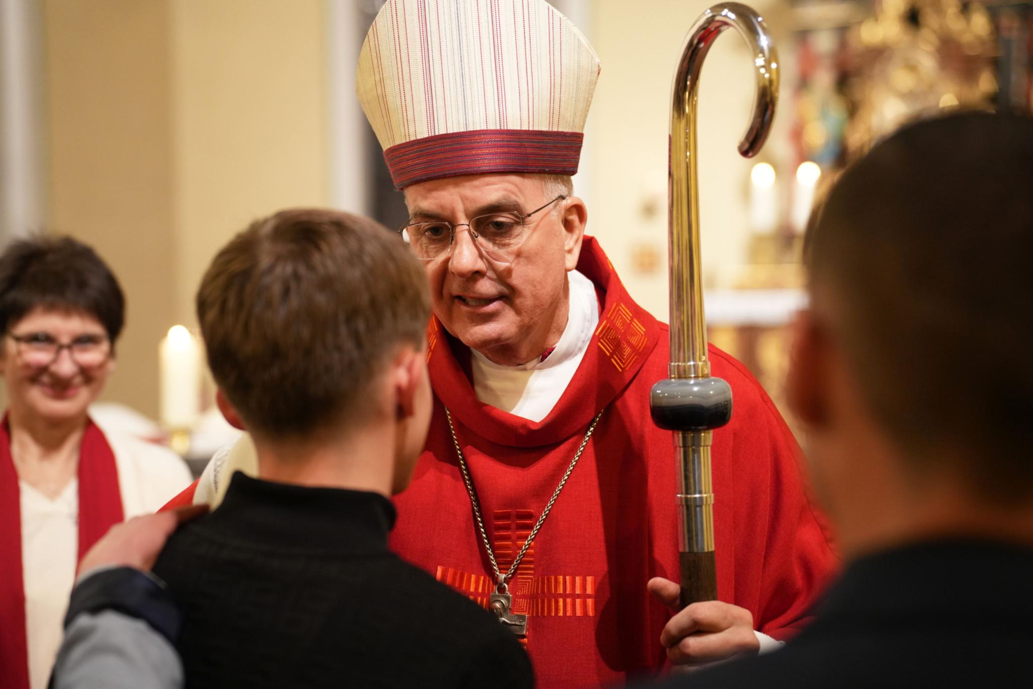 Weihbischof Peters spendet den jungen Menschen in der Kirche St. Maximin in Bettingen das Firmsakrament.